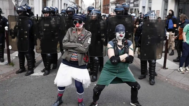 Protestatari îmbrăcați în clown pozând în fața forțelor de poliție în Lille, Franța, în timpul protestelor care au avut loc pe 1 mai