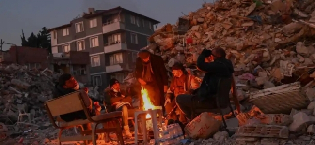 Locuitorii din Hatay, Turcia, ai căror apropiați sunt încă sub dărâmături se adună în jurul unui foc de tabără lângă clădirile prăbușite