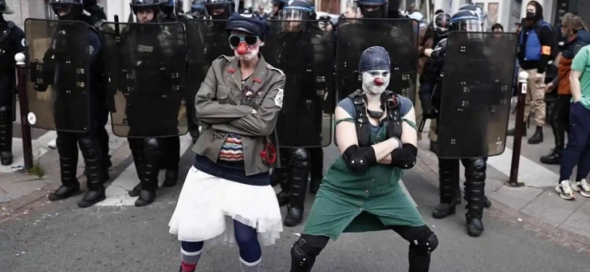 Protestatari îmbrăcați în clown pozând în fața forțelor de poliție în Lille, Franța, în timpul protestelor care au avut loc pe 1 mai